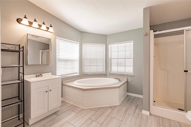 full bathroom with baseboards, a shower stall, a bath, and vanity