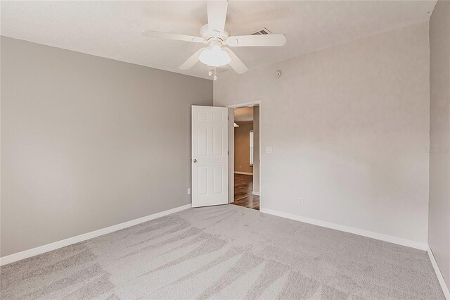 carpeted empty room featuring ceiling fan and baseboards