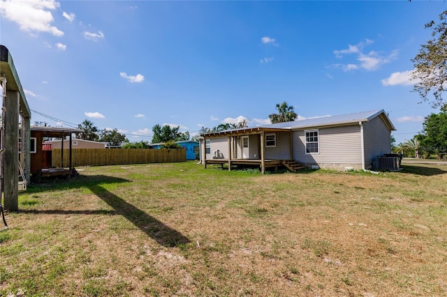 back of house featuring fence, a deck, central AC unit, metal roof, and a lawn