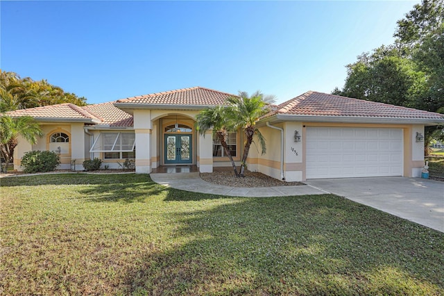 mediterranean / spanish-style house featuring an attached garage, a tile roof, stucco siding, a front yard, and french doors