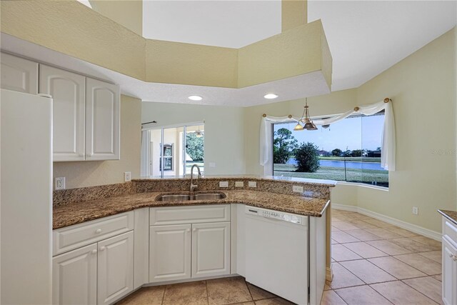 kitchen featuring white appliances, white cabinetry, a sink, and dark stone countertops