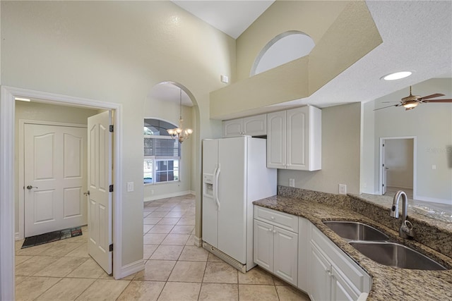 kitchen featuring a sink, light tile patterned floors, white fridge with ice dispenser, and white cabinetry