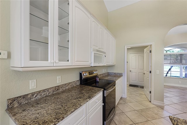 kitchen featuring glass insert cabinets, white microwave, white cabinetry, light tile patterned floors, and stainless steel electric range oven