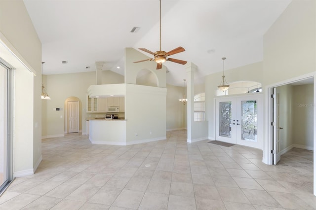 unfurnished living room with visible vents, high vaulted ceiling, french doors, arched walkways, and ceiling fan with notable chandelier