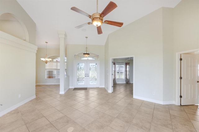 interior space with light tile patterned flooring, high vaulted ceiling, french doors, ceiling fan with notable chandelier, and baseboards