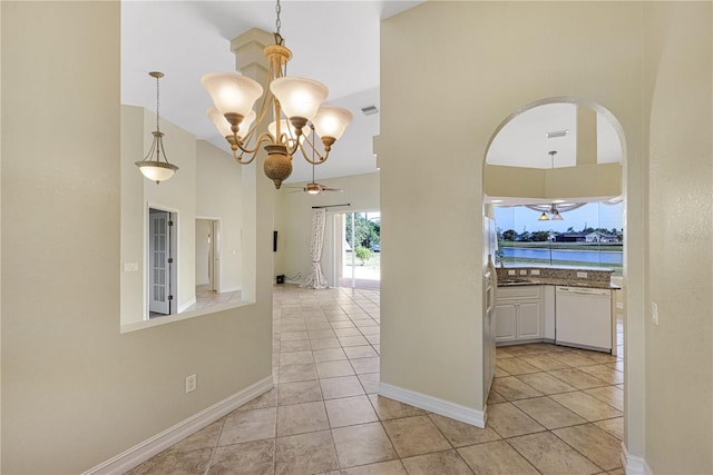 hallway featuring visible vents, a high ceiling, arched walkways, light tile patterned floors, and a notable chandelier