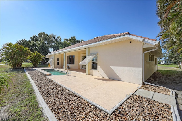 rear view of property with an outdoor pool, a patio area, and stucco siding