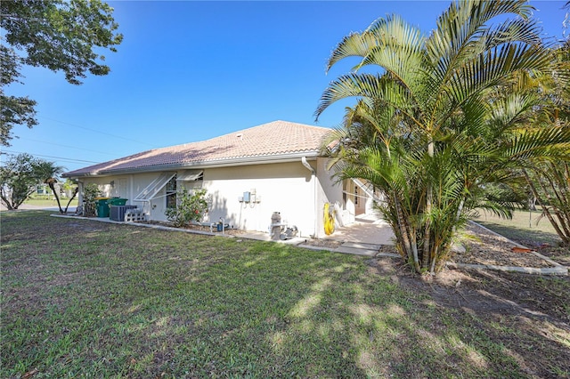 exterior space with a lawn, central AC, stucco siding, and a tile roof