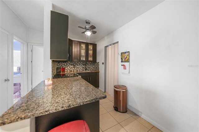 2321 Dallas St, Port Charlotte, FL 33952 - kitchen with decorative backsplash, a ceiling fan, glass insert cabinets, a sink, and light tile patterned floors