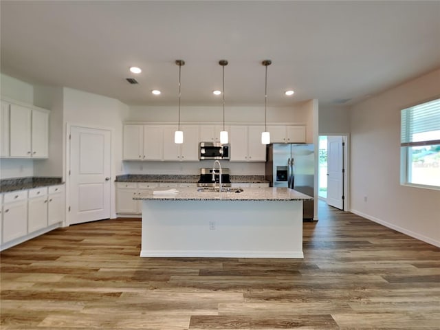 384 Prineville St, Port Charlotte, FL 33954 - kitchen with stainless steel appliances, a sink, a kitchen island with sink, white cabinets, and wood finished floors