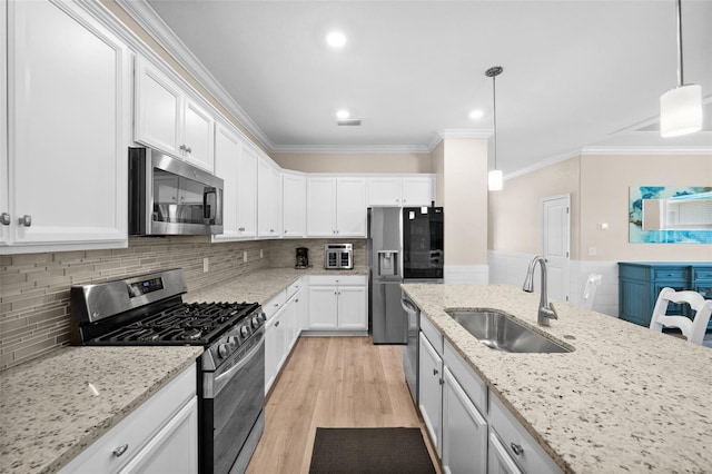 kitchen featuring crown molding, white cabinetry, appliances with stainless steel finishes, and a sink
