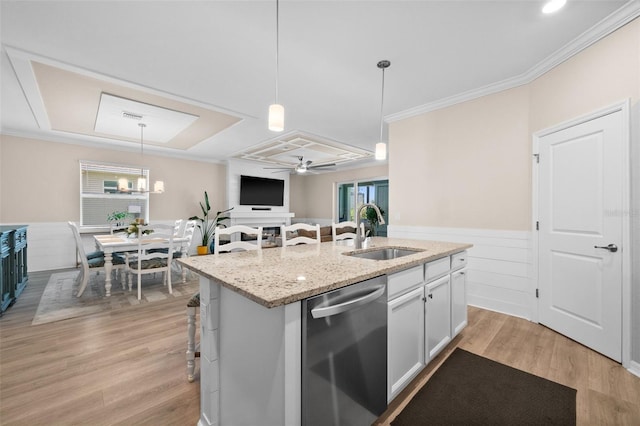 kitchen with a sink, a wainscoted wall, stainless steel dishwasher, and light wood finished floors