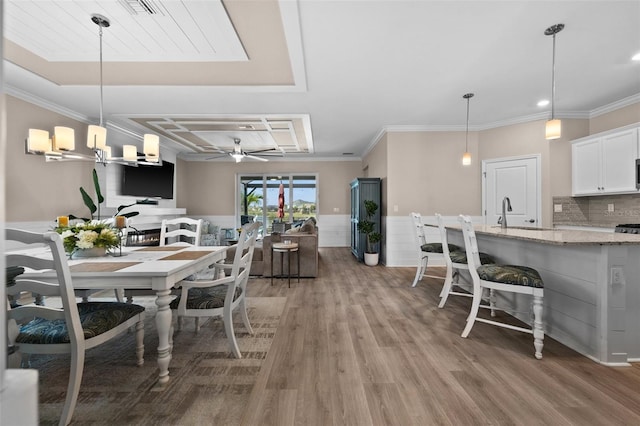 dining area featuring a ceiling fan, light wood finished floors, and ornamental molding