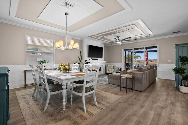 dining room featuring visible vents, light wood-style floors, crown molding, and a wainscoted wall