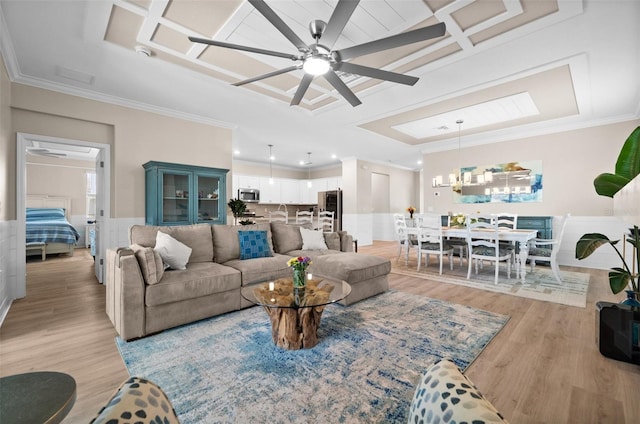 living room featuring light wood-type flooring, a ceiling fan, coffered ceiling, and crown molding