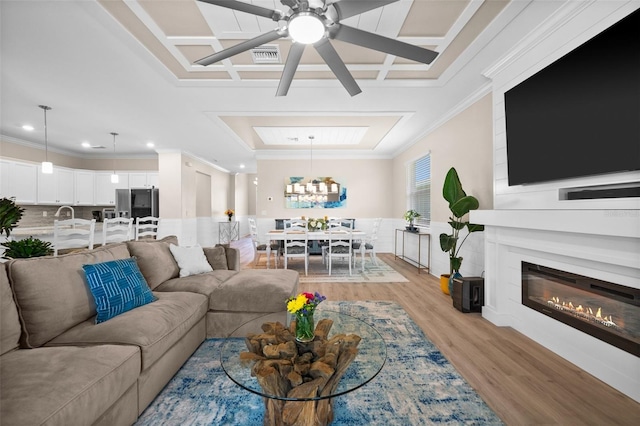 living room with crown molding, light wood finished floors, ceiling fan with notable chandelier, and coffered ceiling