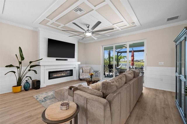 living room featuring visible vents, a glass covered fireplace, ceiling fan, and a wainscoted wall