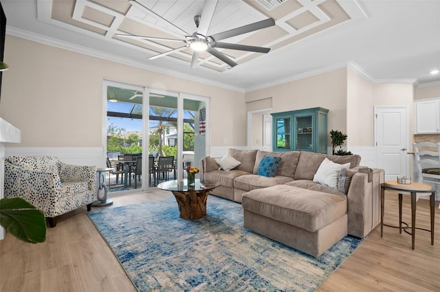 living area featuring wainscoting, a ceiling fan, ornamental molding, and light wood-style flooring