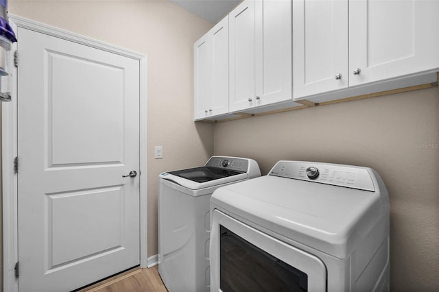 laundry area featuring light wood-style floors, cabinet space, and washing machine and dryer