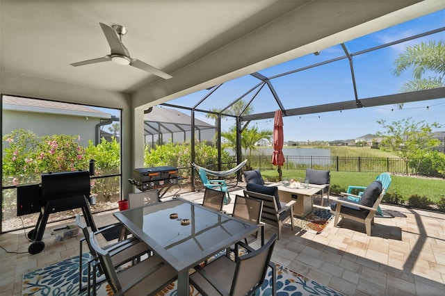 view of patio / terrace featuring fence, outdoor dining area, a water view, an outdoor fire pit, and a lanai
