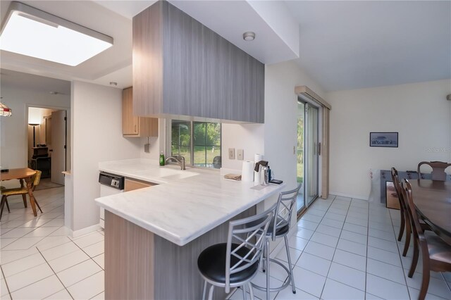 2113 Barksdale St, Port Charlotte, FL 33948 - kitchen with light countertops, light tile patterned floors, a breakfast bar, a peninsula, and dishwasher