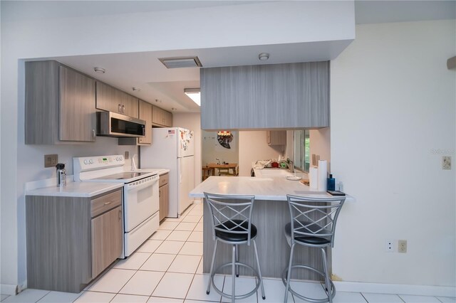 2113 Barksdale St, Port Charlotte, FL 33948 - kitchen featuring white appliances, a breakfast bar area, a peninsula, and light countertops
