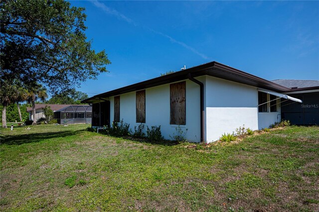 2113 Barksdale St, Port Charlotte, FL 33948 - view of side of property featuring a yard, stucco siding, and glass enclosure