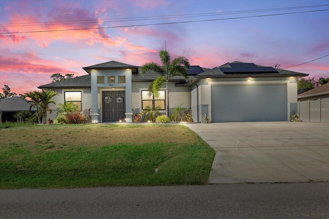 prairie-style home featuring an attached garage, roof mounted solar panels, stucco siding, and driveway