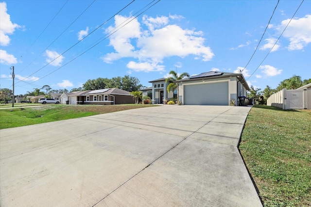 view of front of house with a front yard, a gate, concrete driveway, an attached garage, and solar panels
