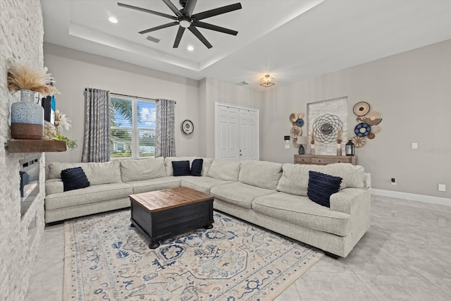 living area featuring ceiling fan, light tile patterned floors, baseboards, a tray ceiling, and recessed lighting