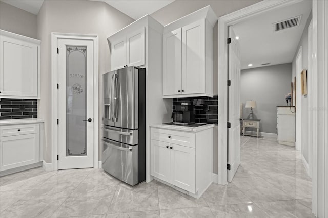 kitchen featuring backsplash, stainless steel refrigerator with ice dispenser, visible vents, white cabinets, and marble finish floor