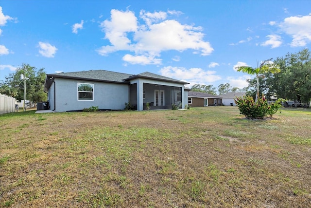 rear view of property featuring a lawn, stucco siding, and cooling unit