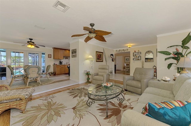 living room with visible vents, crown molding, baseboards, light wood-type flooring, and a ceiling fan
