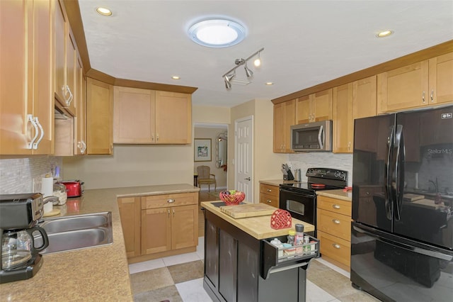 kitchen with light countertops, backsplash, black appliances, and a sink