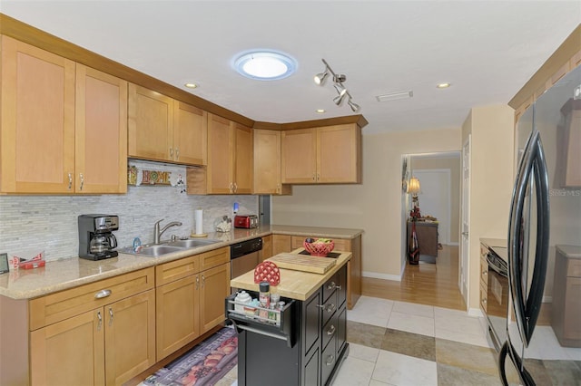 kitchen with a sink, light countertops, tasteful backsplash, and fridge