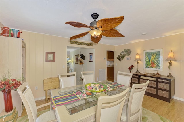 dining area with ceiling fan, light wood finished floors, and visible vents
