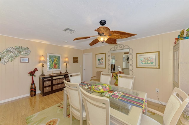 dining area featuring light wood-style floors, baseboards, ceiling fan, and visible vents