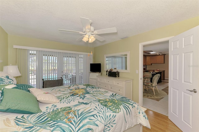 bedroom featuring visible vents, access to exterior, a textured ceiling, a ceiling fan, and light wood-style flooring