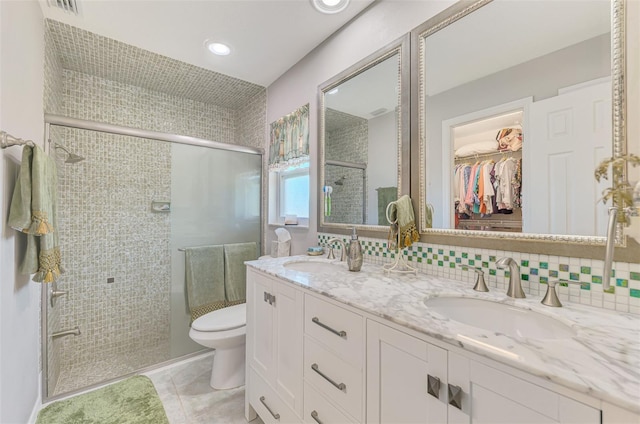 full bathroom featuring a sink, a shower stall, toilet, and double vanity