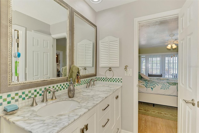 ensuite bathroom with a sink, a ceiling fan, wood finished floors, and connected bathroom