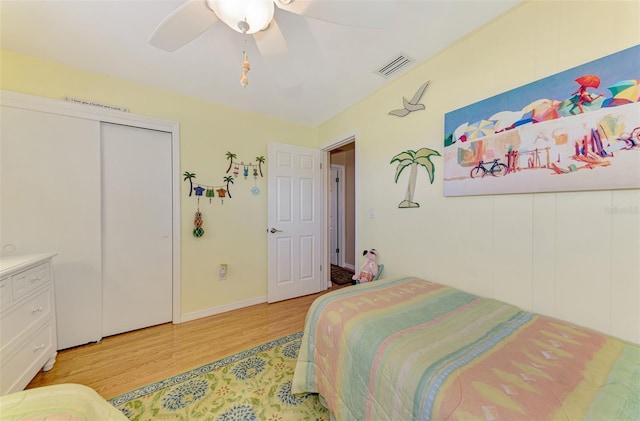 bedroom featuring a ceiling fan, baseboards, light wood-type flooring, visible vents, and a closet