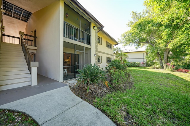 back of property with stairs, a lawn, and stucco siding