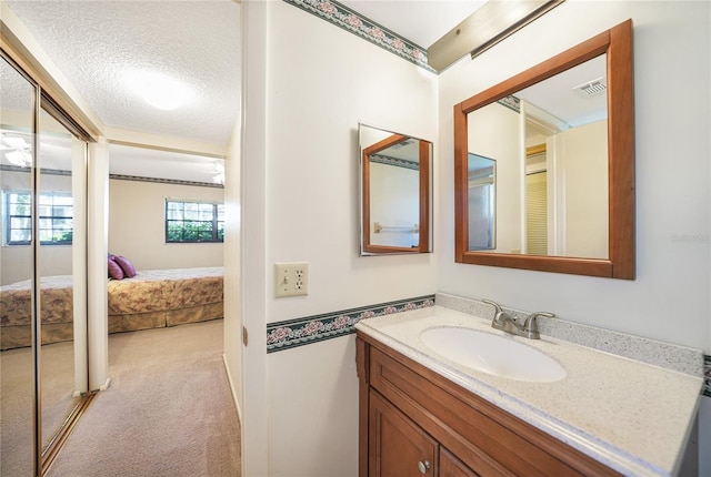 ensuite bathroom with vanity, a textured ceiling, ensuite bathroom, and visible vents