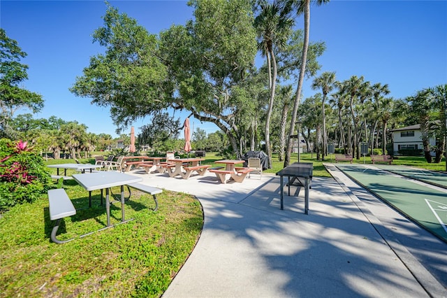 view of community featuring a lawn and shuffleboard