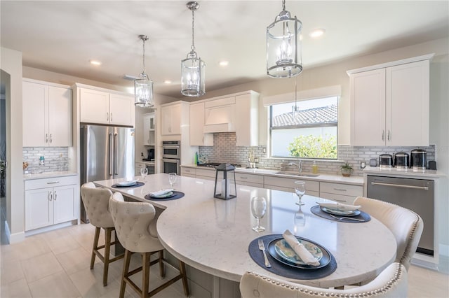 6763 Winding Cypress Dr, Naples, FL 34114 - kitchen with a breakfast bar, a sink, premium range hood, stainless steel appliances, and backsplash