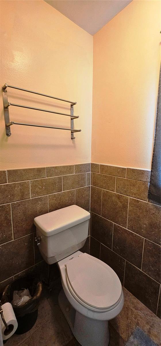 570 Mimosa Ave NW, Port Charlotte, FL 33952 - half bath featuring toilet, tile walls, and wainscoting