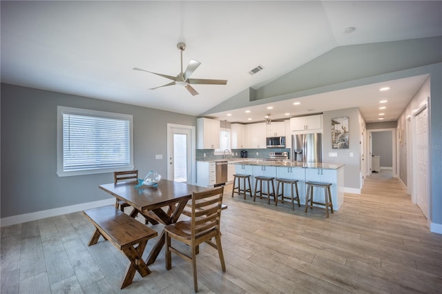 dining space featuring vaulted ceiling, ceiling fan, baseboards, and light wood finished floors