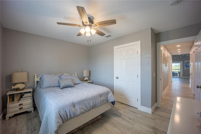 bedroom featuring baseboards, ceiling fan, light wood finished floors, and visible vents