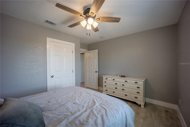 bedroom with baseboards, ceiling fan, light wood-style floors, and visible vents