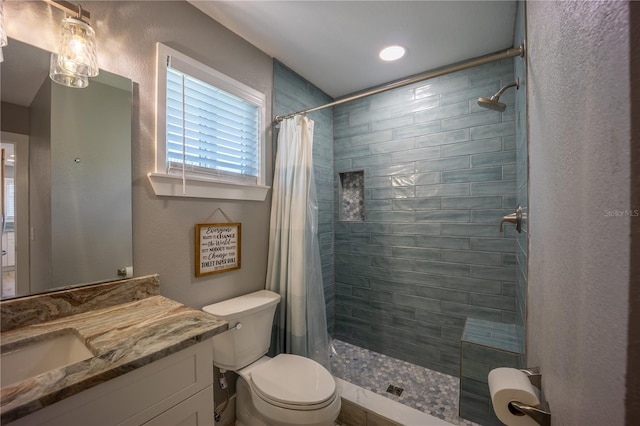 bathroom featuring a tile shower, vanity, and toilet